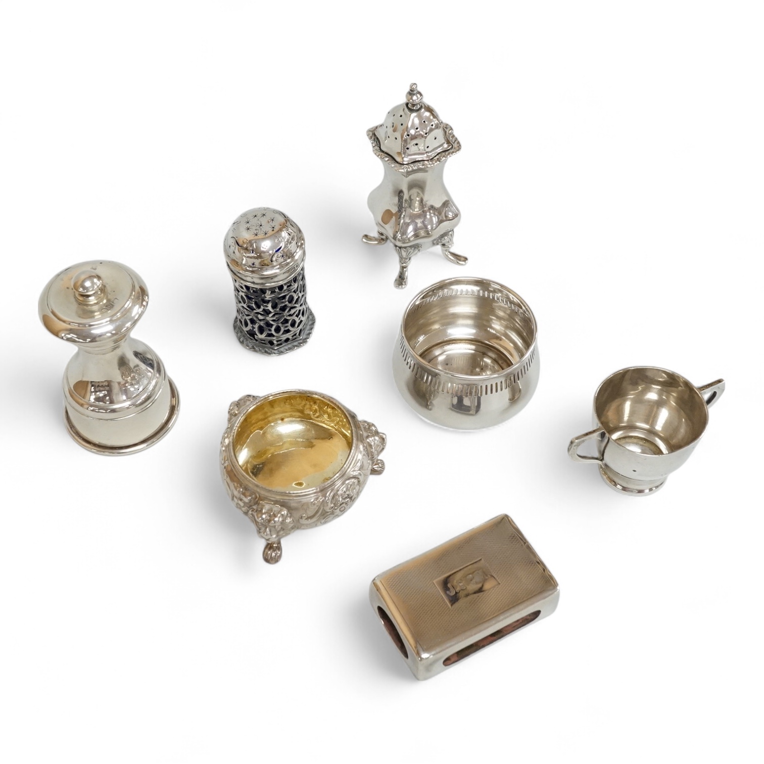 Four assorted silver condiments including a Victorian bun salt and a late Victorian pepper mill, together with a small silver bowl, a silver matchbox sleeve and a small silver two handled cup.